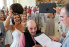 My daughter-in-law ripped off my wife’s wig at my son’s wedding, revealing the traces of months of treatment while some guests laughed. I went on stage, covered my wife with my jacket, and opened the wedding envelope… When she saw the documents inside, her smile suddenly…